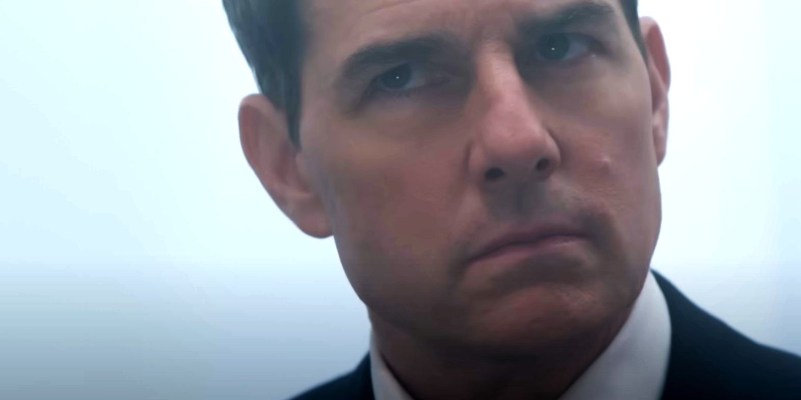 Tom Cruise as Ethan Hunt cocking head in front of white background in Mission Impossible 7