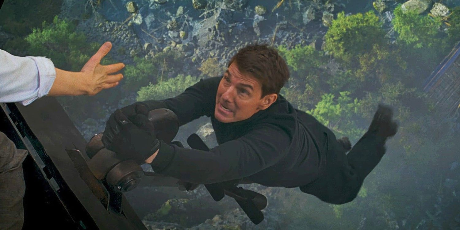 Tom Cruise hanging off a train with a hand reaching out to him in Mission Impossible Dead Reckoning Part One