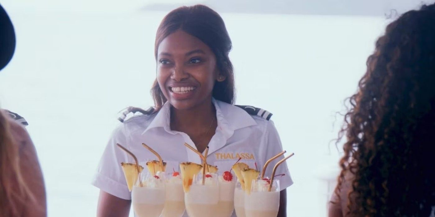 A crew member smiles over a tray of drinks on Below Deck