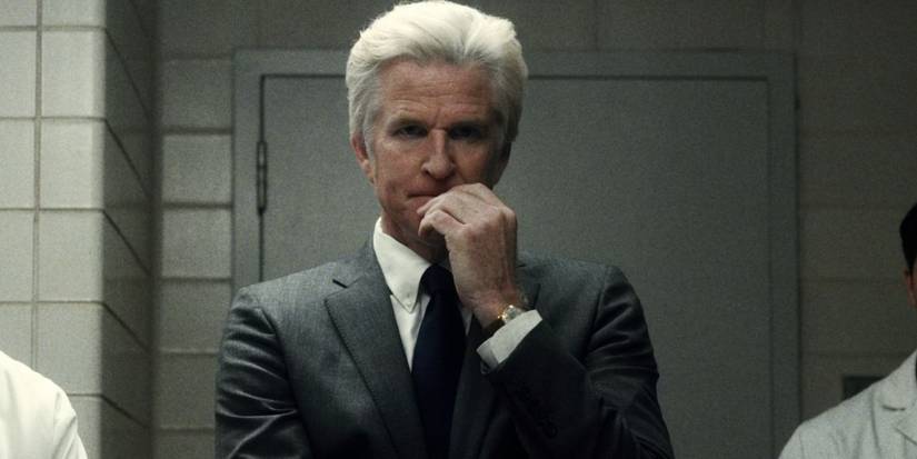 Matthew Modine as Dr. Martin Brenner looking intrigued with his hand over his mouth in Stranger Things