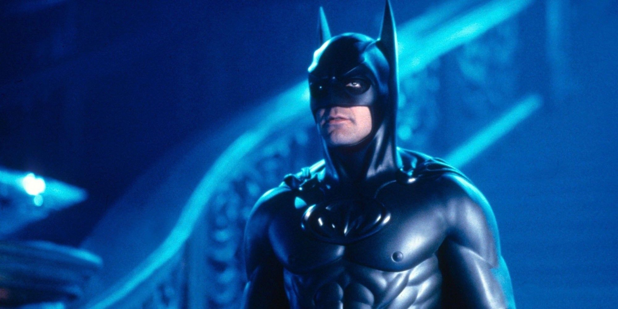 George Clooney as Batman looking heroic in a blue room in Batman & Robin.