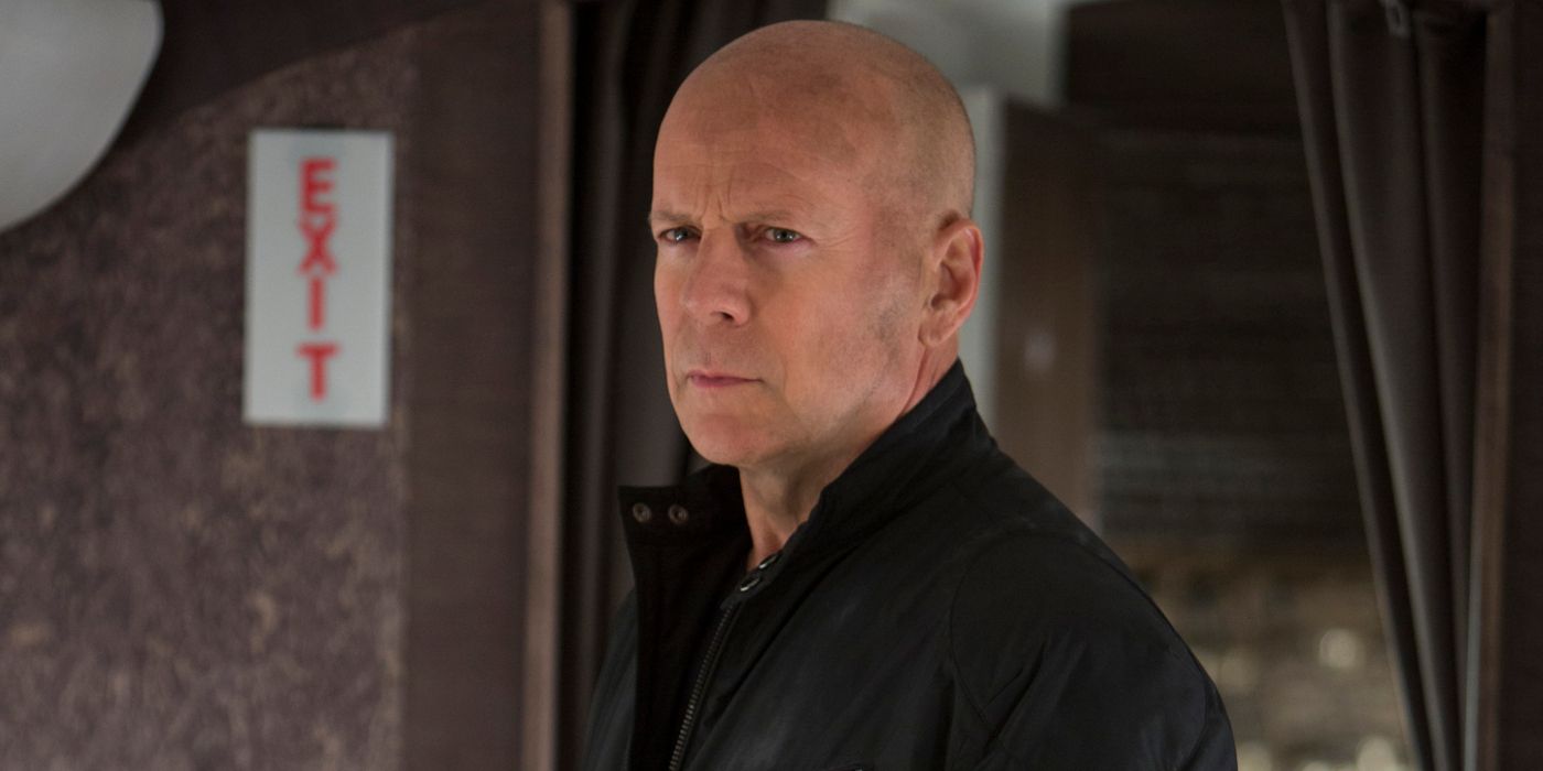 Frank, played by Bruce Willis, stands near the exit on an airplane in Red 2.