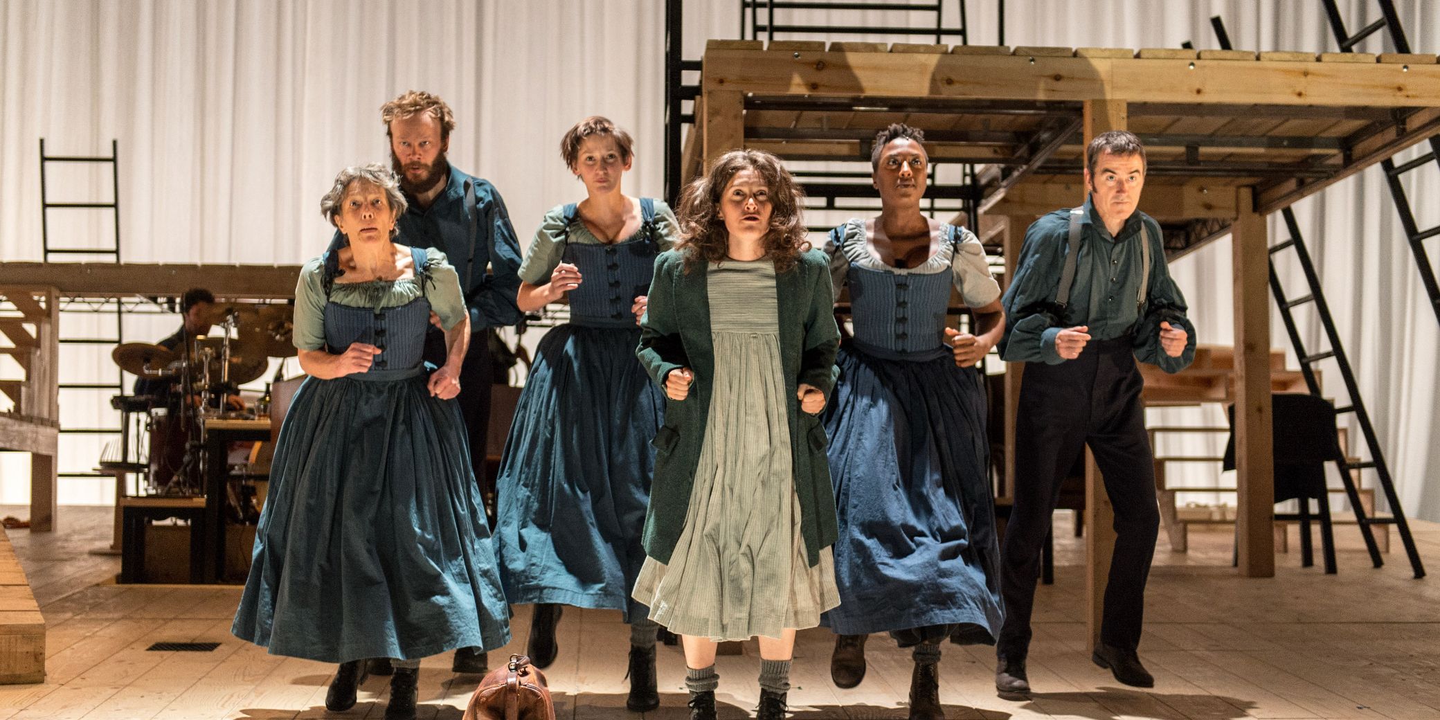 Cast members walking in place in front of platforms with steps and ladders attached in the Jane Eyre 2015 UK National Theater production