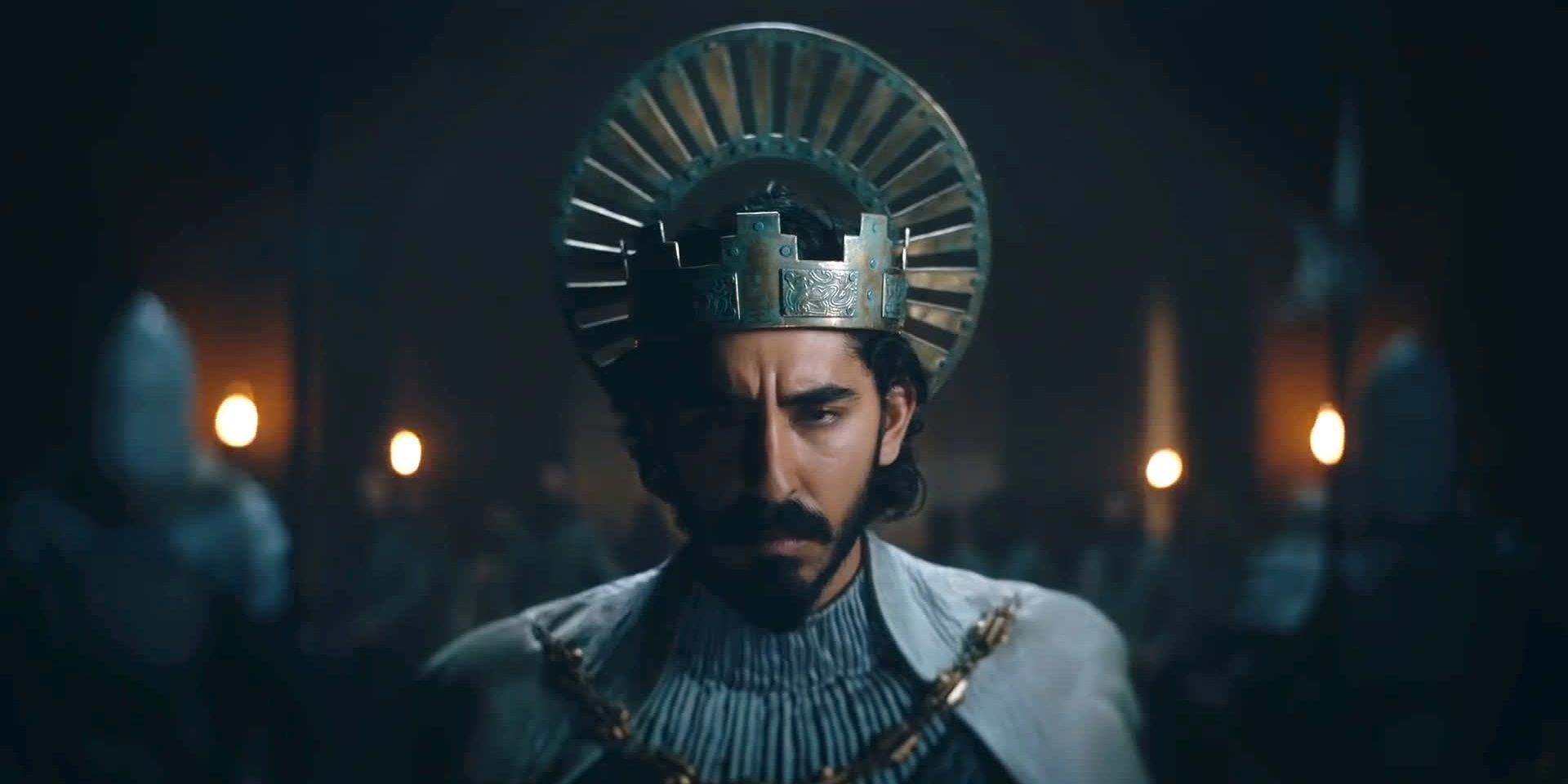 Dev Patel in a Crown Looking Serious in The Green Knight
