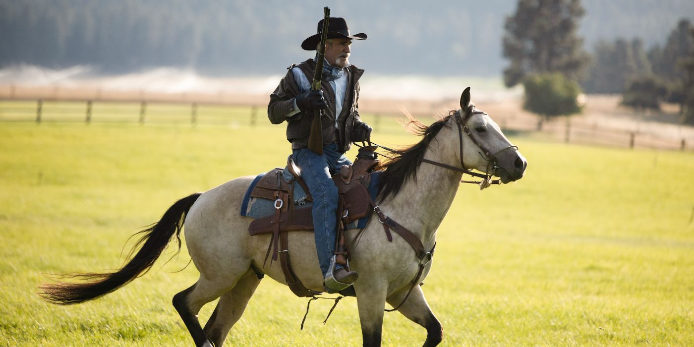 Forrie J Smith as Lloyd Pierce riding a horse and holding a gun in Yellowstone.