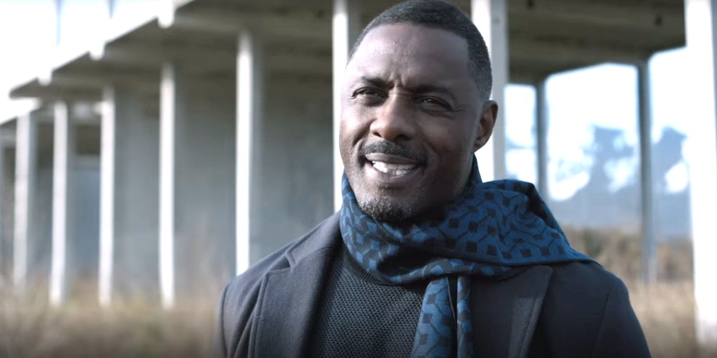 Idris Elba in Extraction 2 wearing a scarf in a field by an overpass, having a conversation