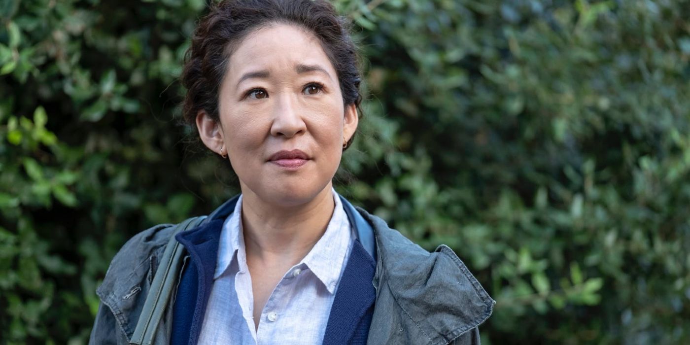 Sandra Oh as Eve in Killing Eve standing in front of greenery and smiling slightly