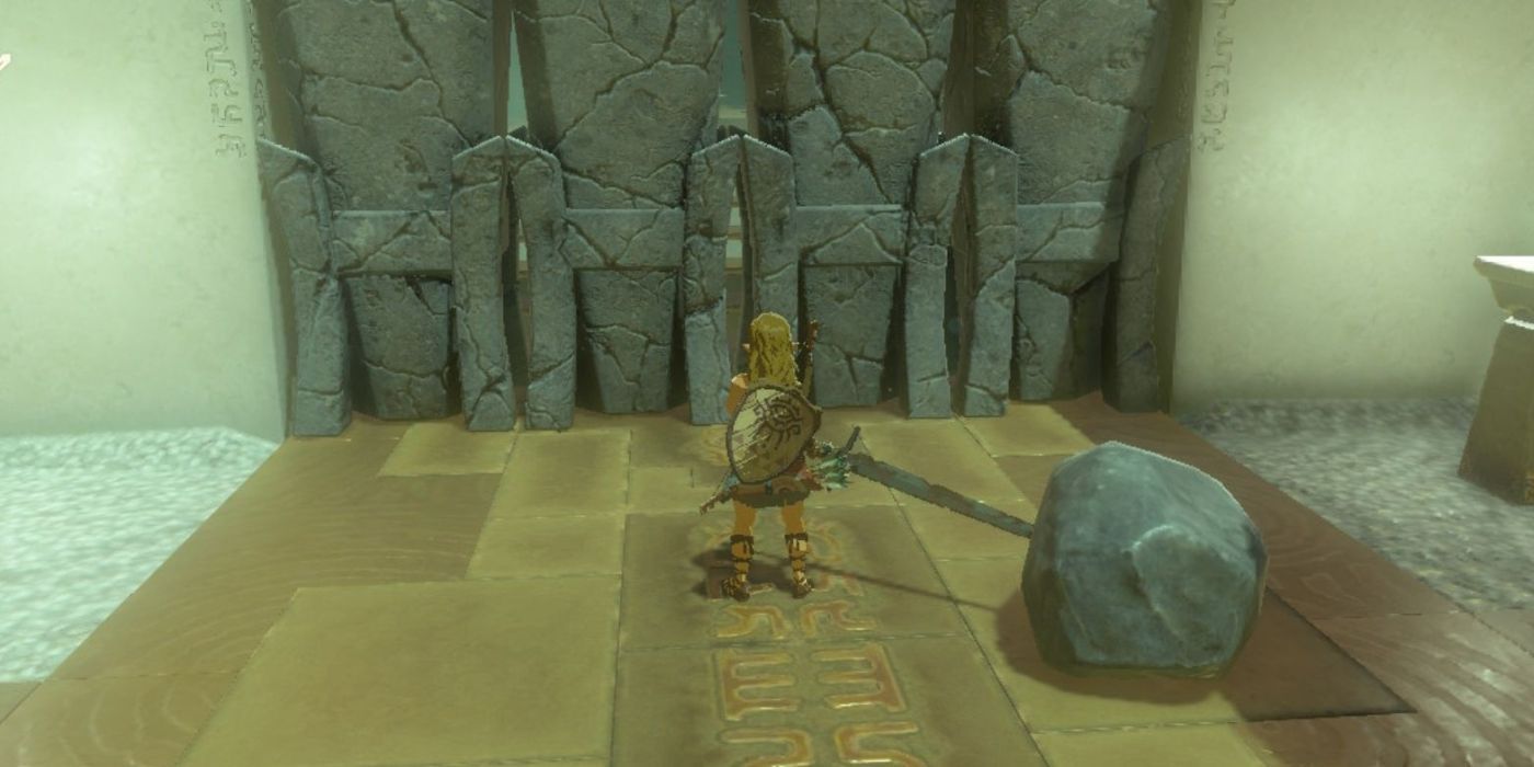 Link berdiri di depan pintu berbatu, memegang pedang yang telah menyatu dengan batu besar di Tears of the Kingdom.