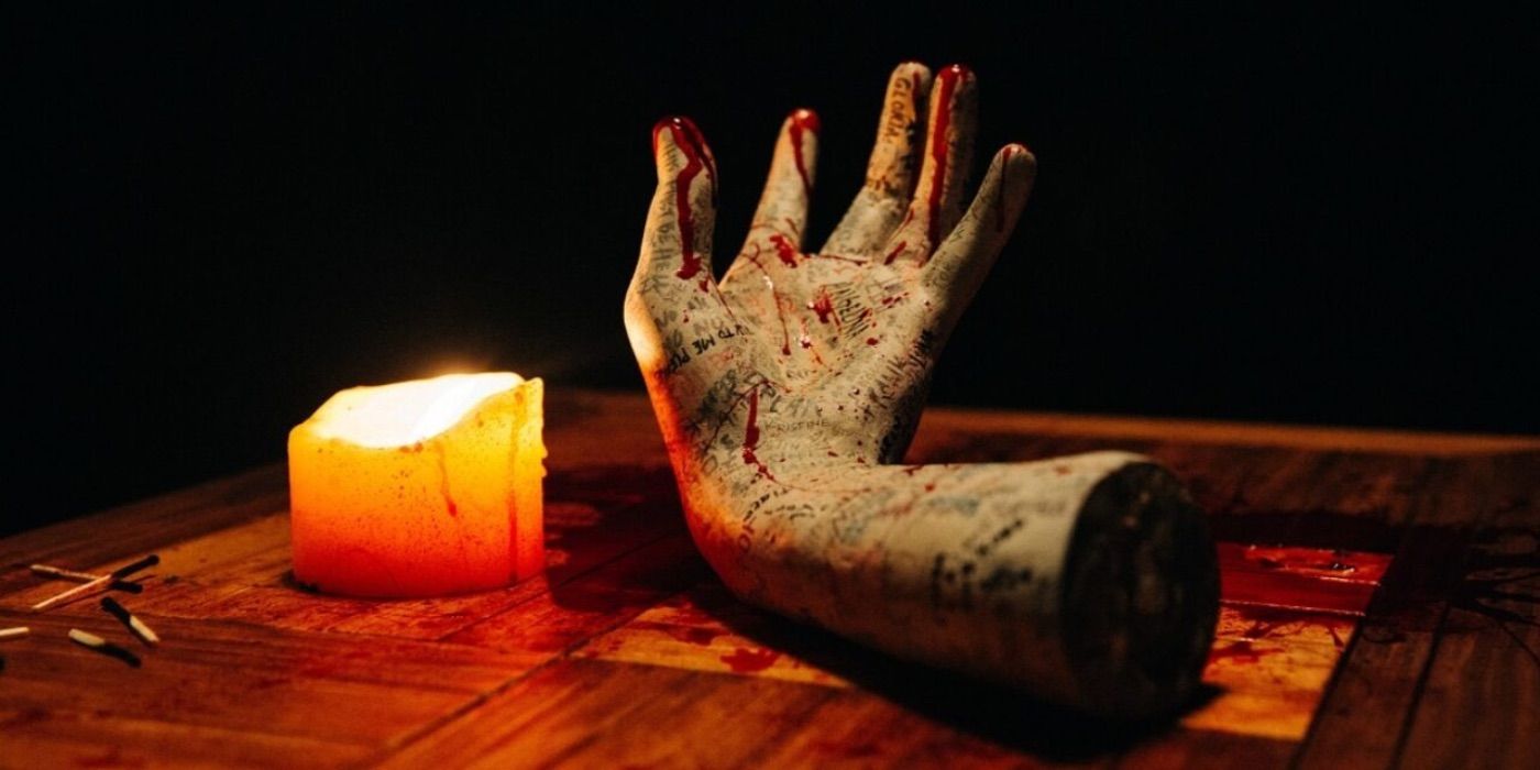 The hand sits next to a candle from Talk to Me