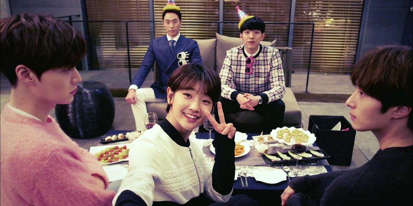 The cast of Cinderella and her Four Knights together in party hats around a table of food