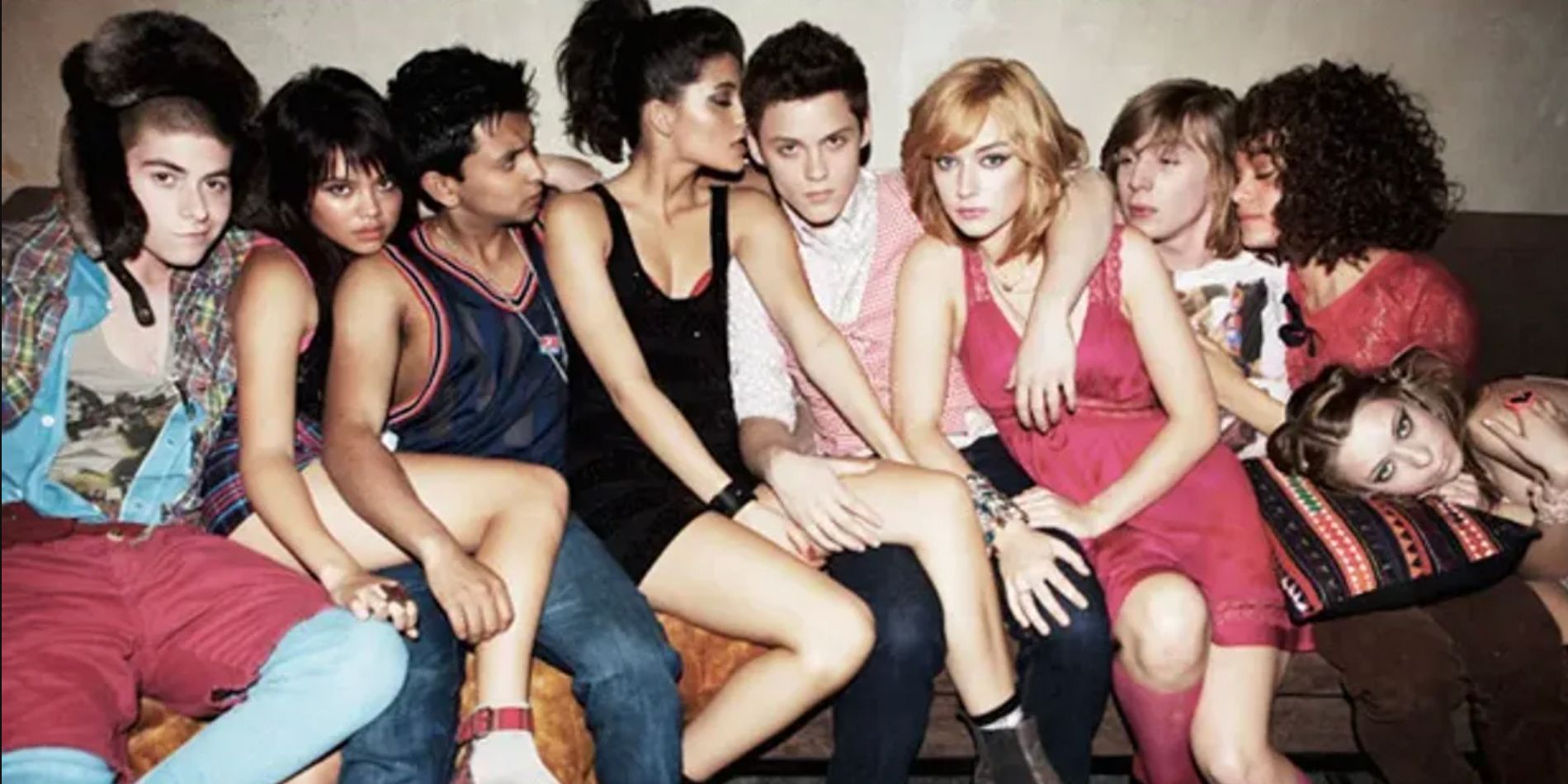 The cast of MTV Skins on a couch with their arms around one another and their legs crossed over one another