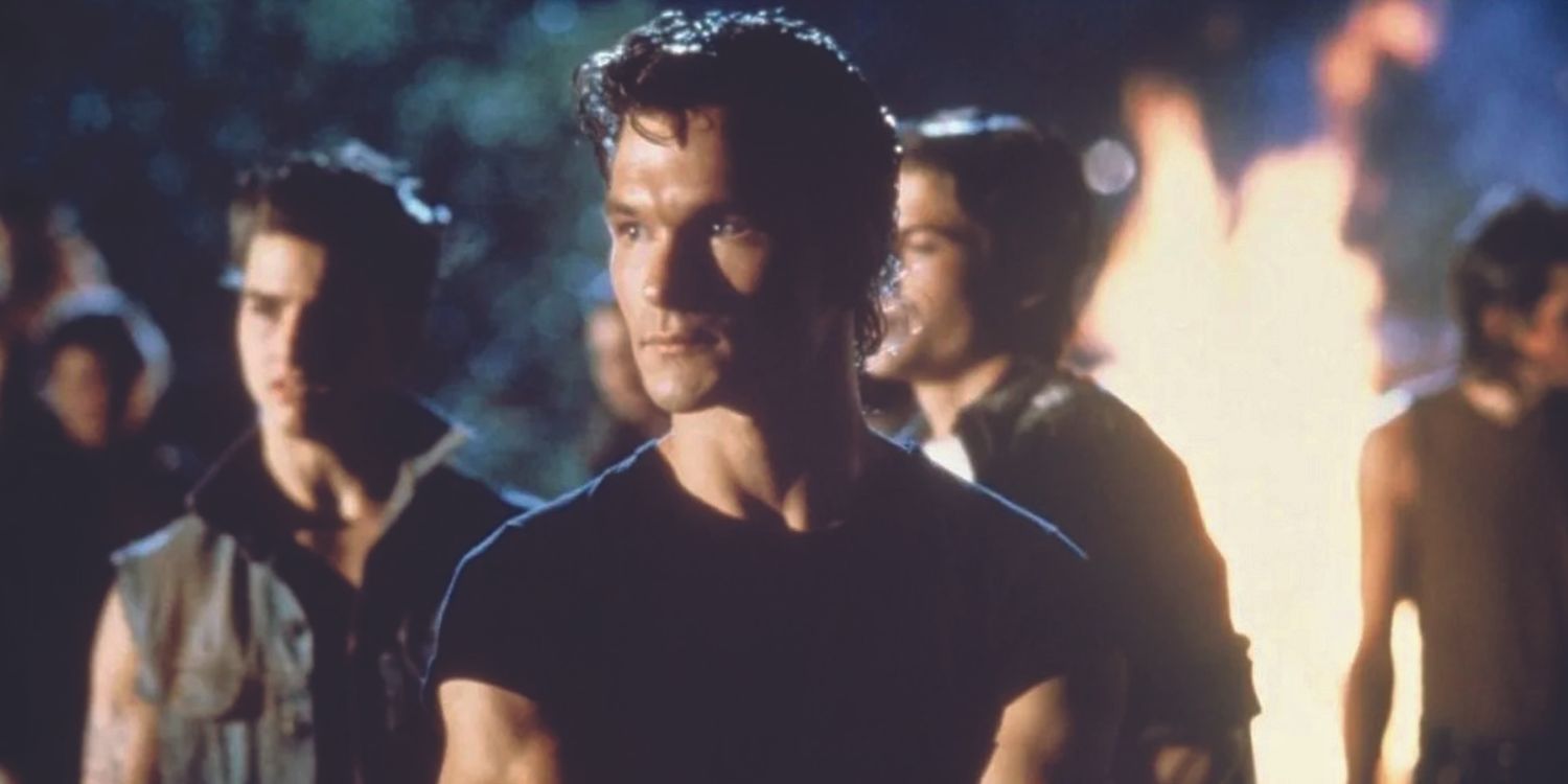 Patrick Swayze standing with his gang at night in The Outsiders