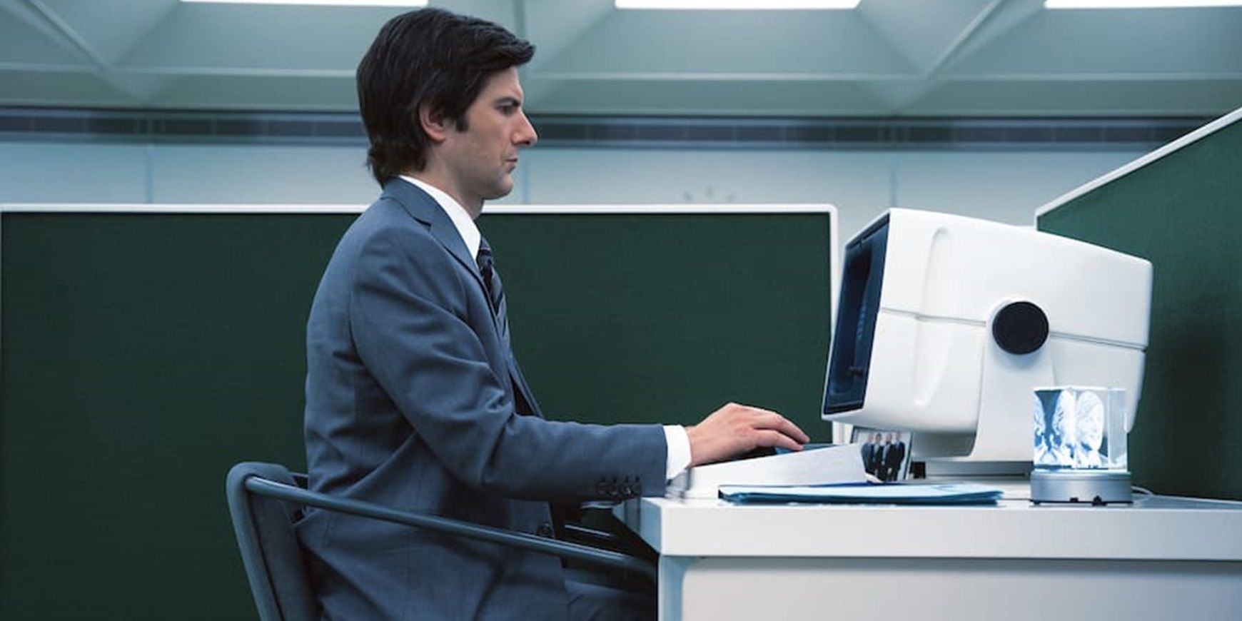 Adam Scott sits at a computer in Severance