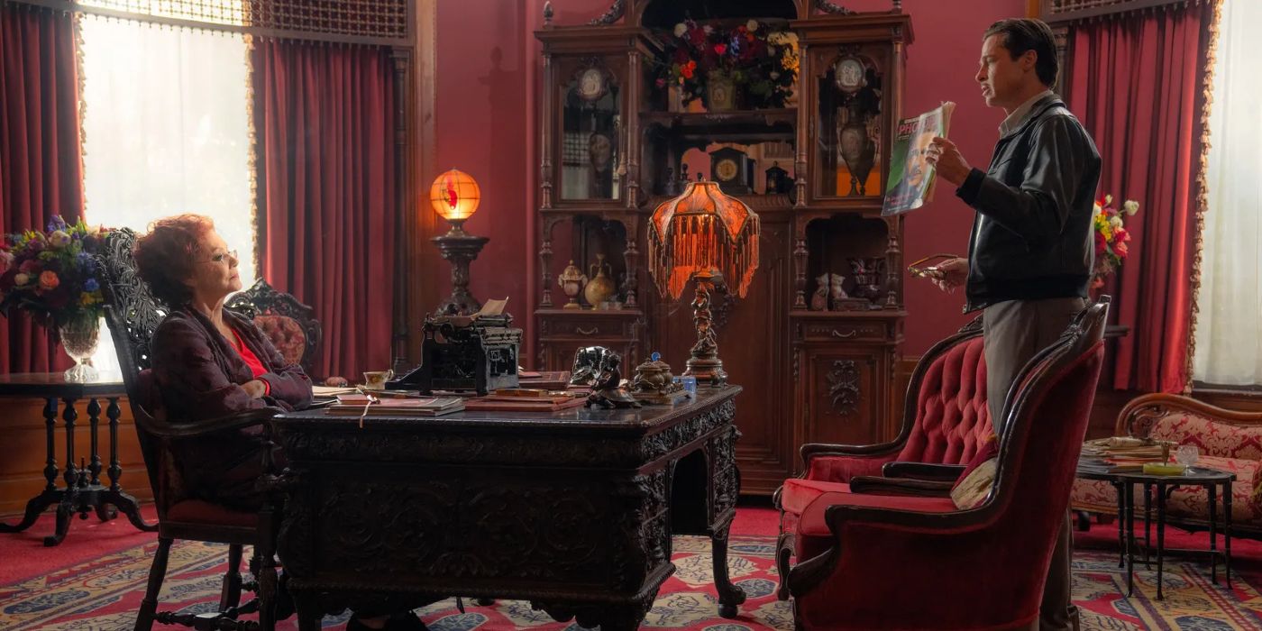 Elinor St. John sits at her desk and looks at a man holding up a news article.