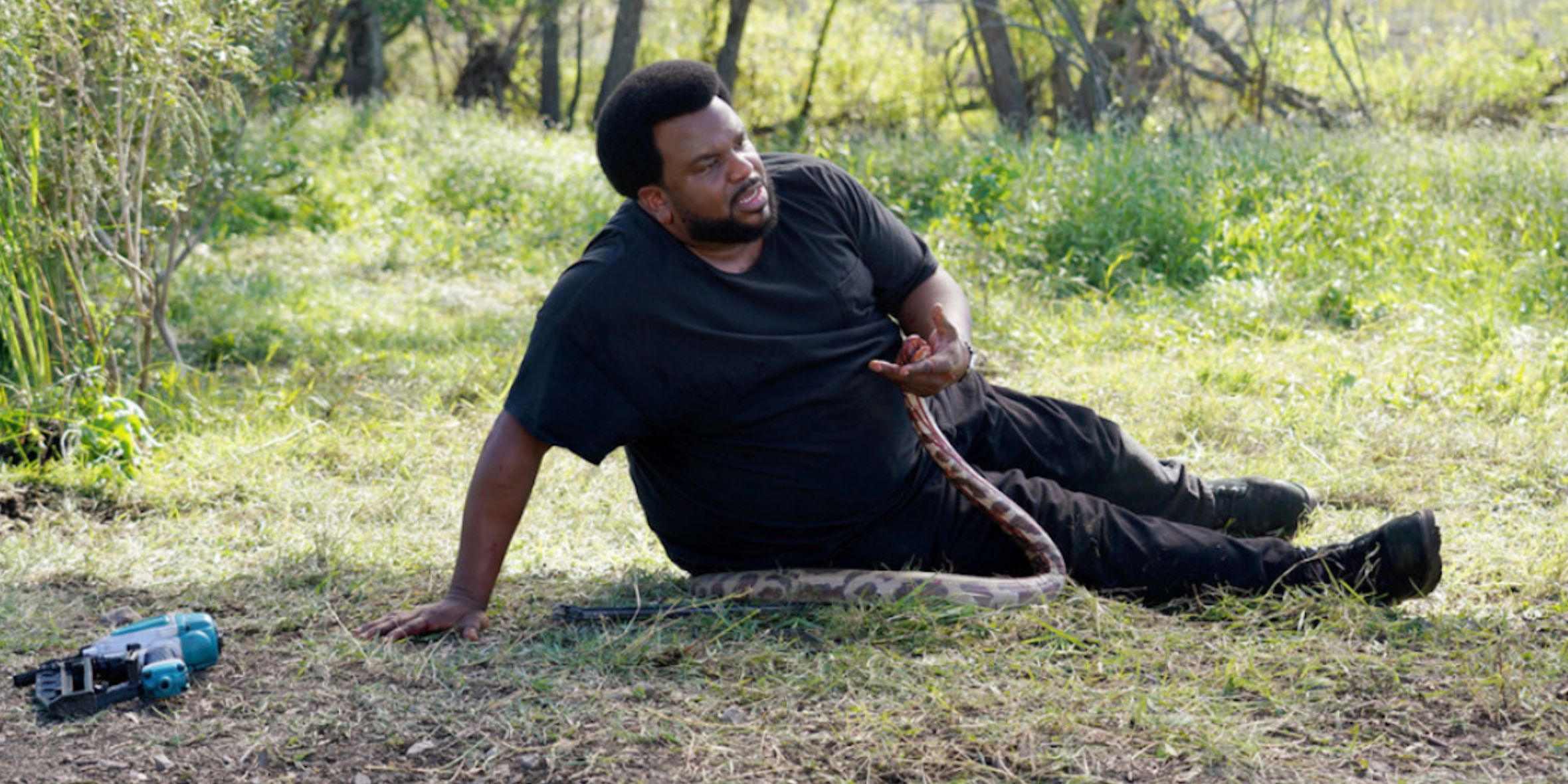 Craig Robinson with a snake on the ground in the series Killing It