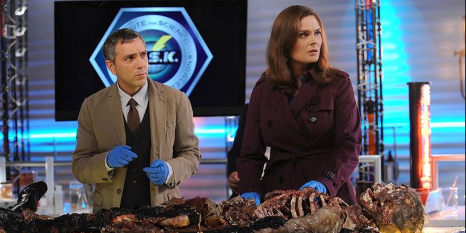 Douglas Filmore alongside Temperance Brennan as they examine remains on a tv show set in Bones