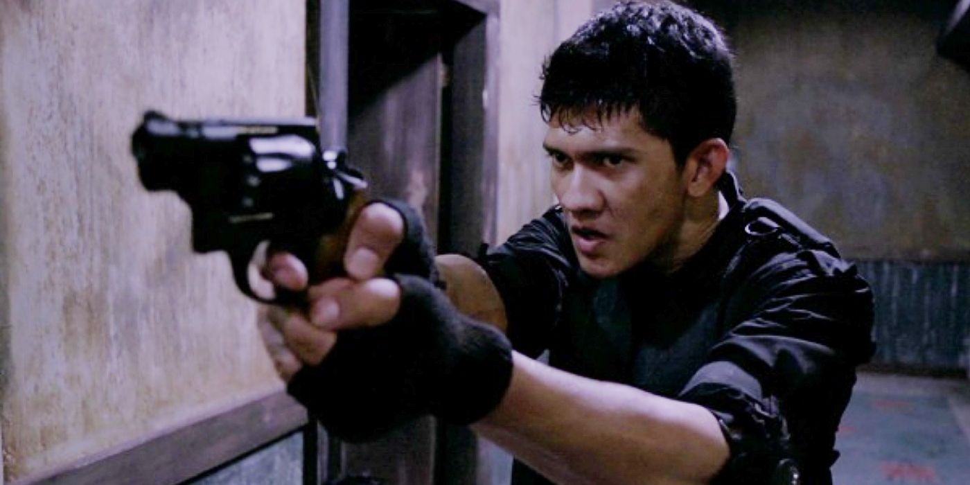 Iko Uwais is seen pointing a gun and looking angry in The Raid: Redemption.