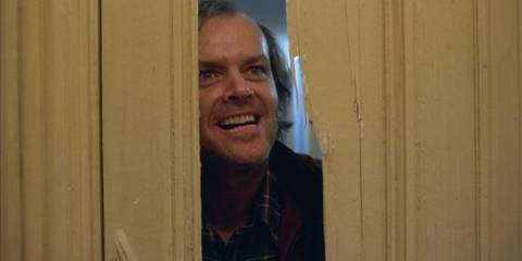 Jack Nicholson as Jack Torrance smiling through the broken door in The Shining
