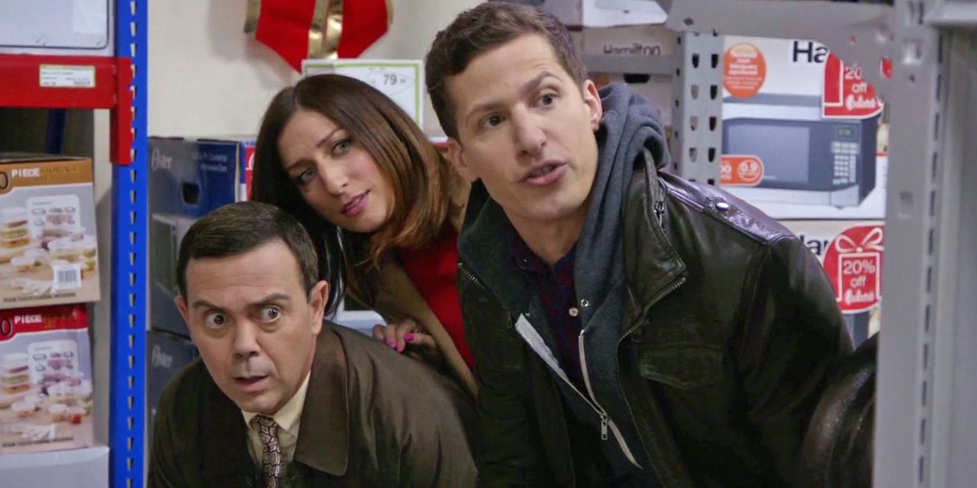 Jake, Amy and Charles in a store, peeking around shelving, in Brooklyn 99.