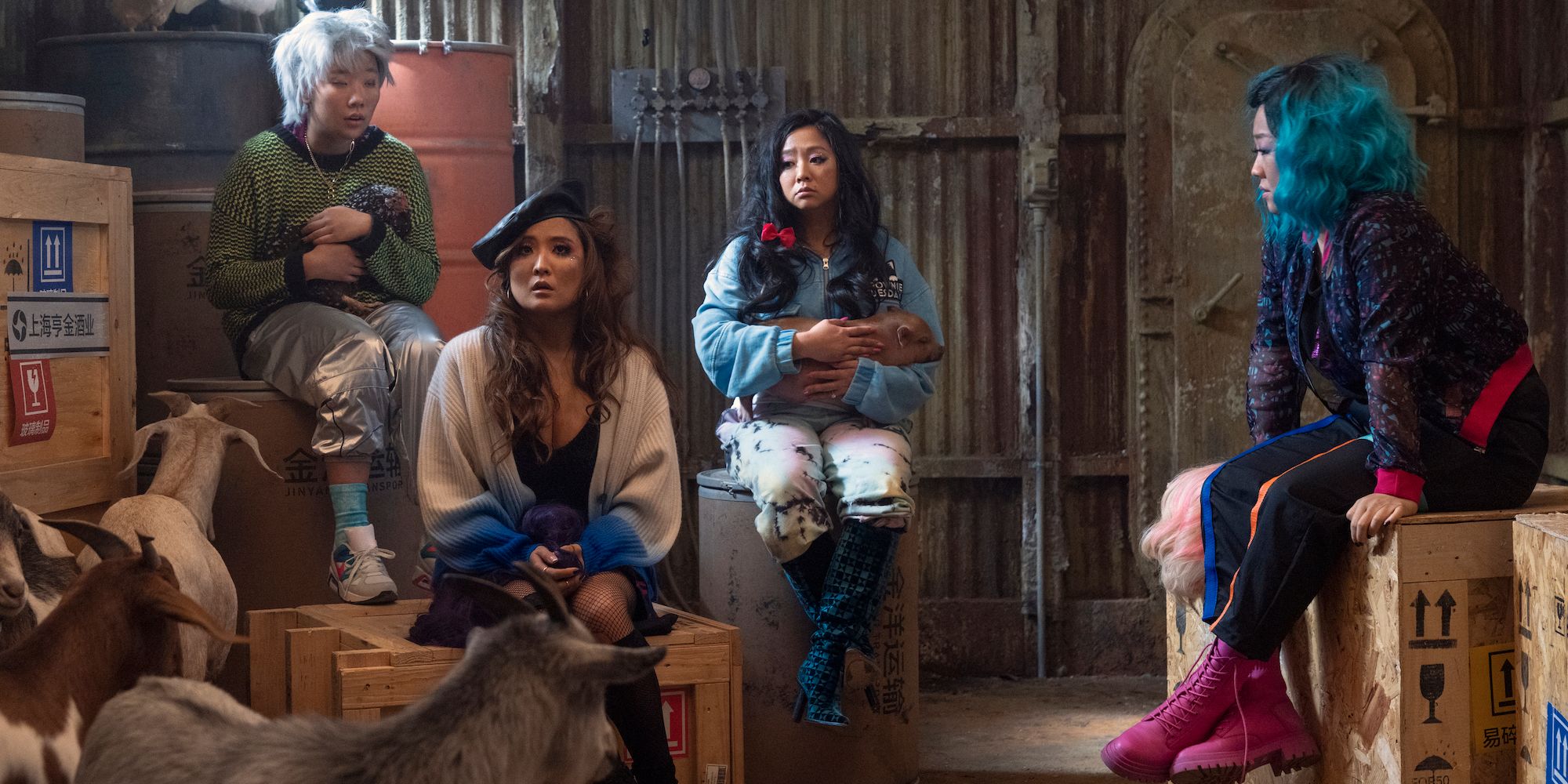 Deadeye, Audrey, Kat, and Lolo sitting on boxes with goats around them in Joy Ride (2023)