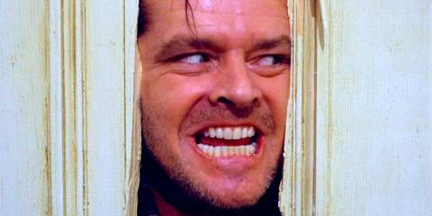 Jack Nicholson smiling as he breaks through a door in The Shining