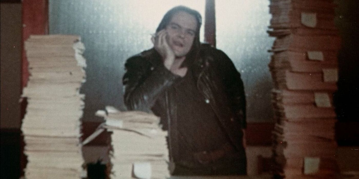 A man leans against a stack of papers in Last House on Dead End Street