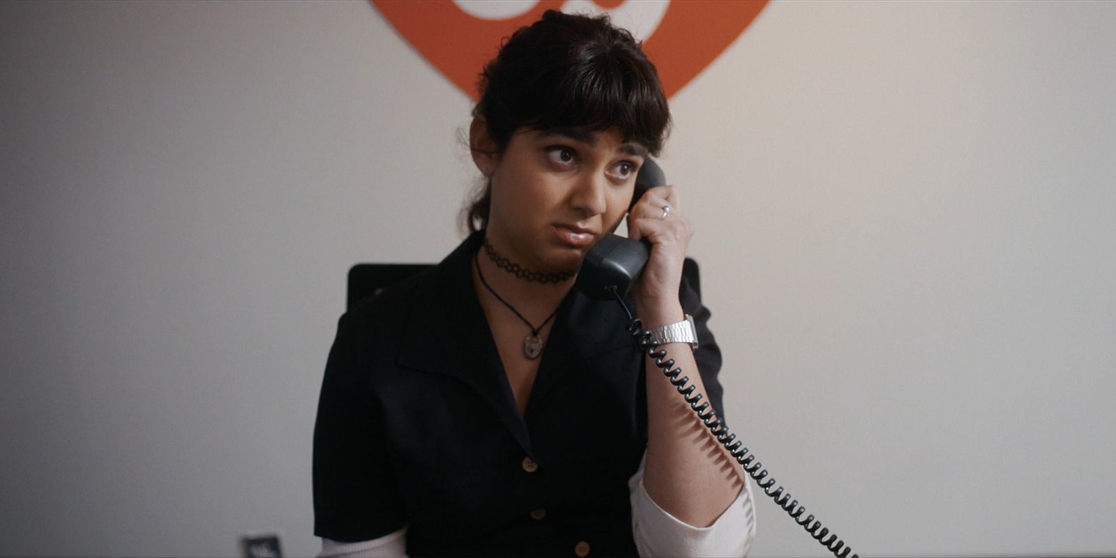 Maya talks on the phone while sitting in front of the Ty Inc symbol.