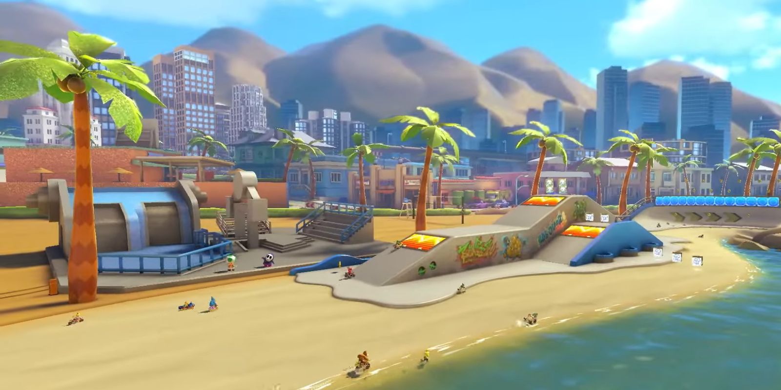 An aerial view of the Los Angeles Laps track in Mario Kart 8, showing racers driving along the beach near a facsimile of the LA skyline.
