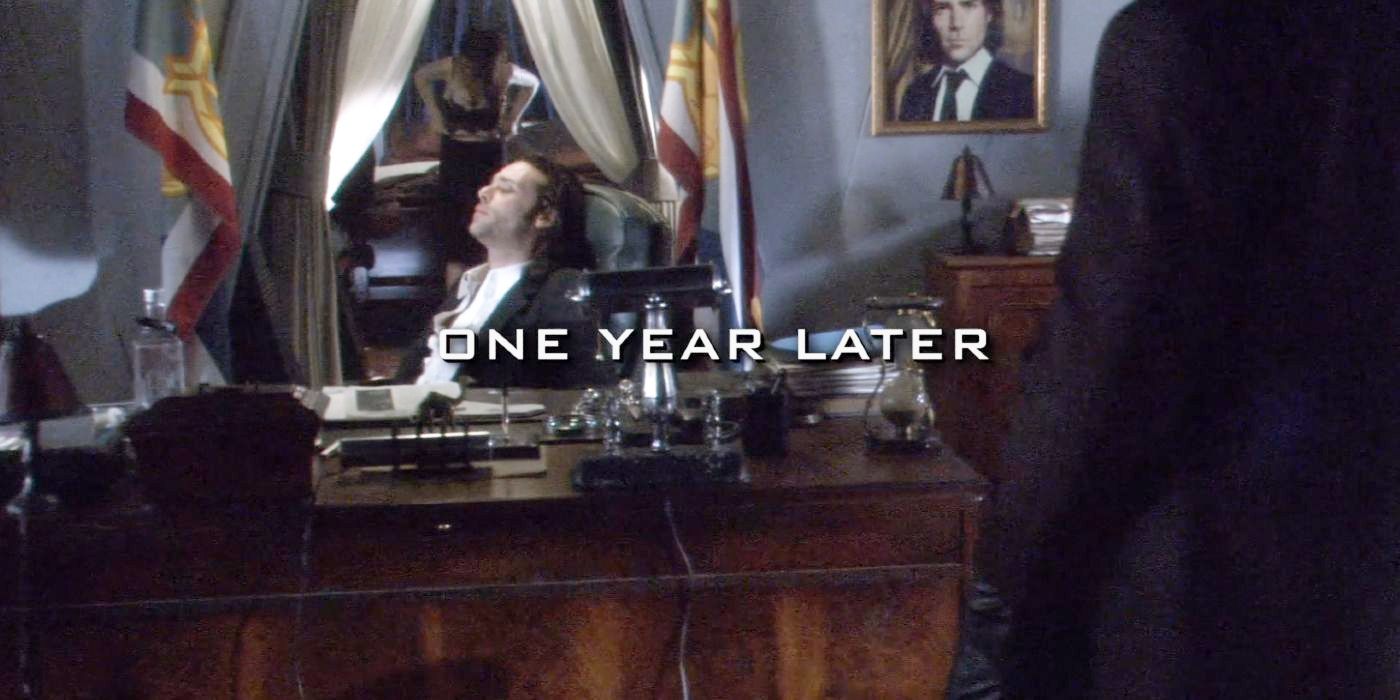 President Fitch sits at his desk with the words &ldquo;one year later&rdquo; on the screen in Battlestar Galactica.