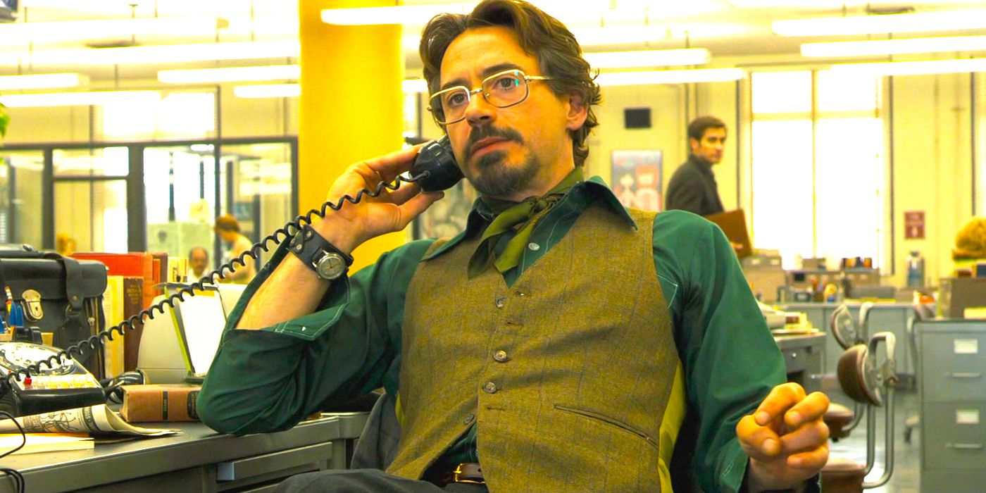 Robert Downey Jr in 60s garb talking on the phone in a bustling newsroom in Zodiac