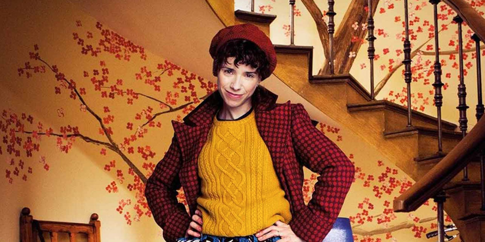 Sally Hawkins šypsosi priešais rudus šeimos laiptus Paddingtone