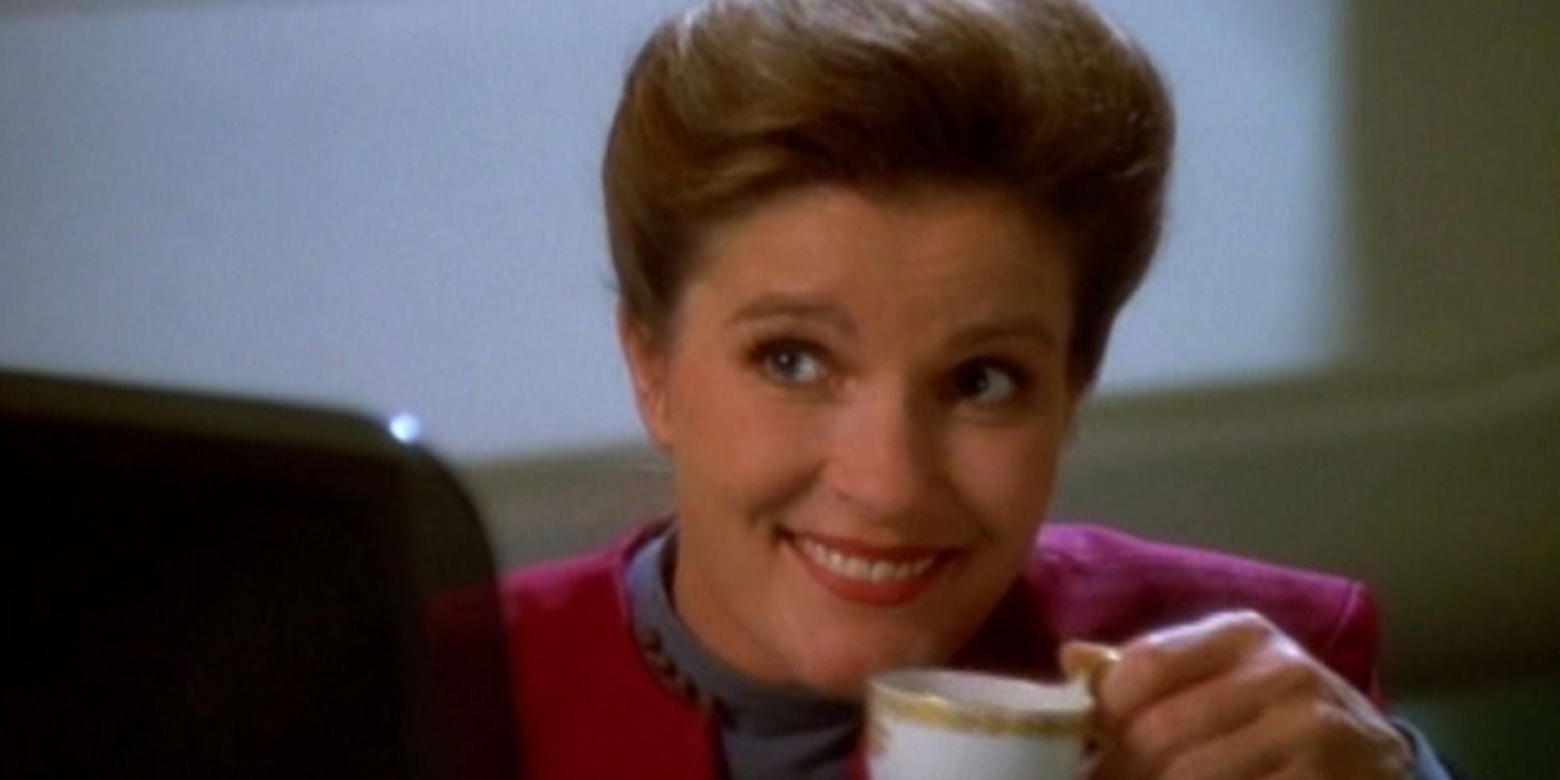 Captain Janeway smiles as she raises a tea cup to her lips in Star Trek: Voyager.