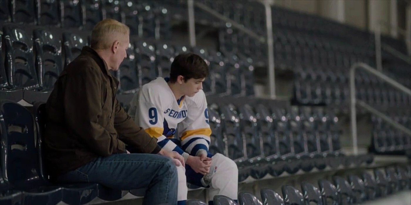 In a scene from The Americans, Stan, a blonde-haired man, is sitting and talking to Henry, a brunette teen boy in a hockey uniform