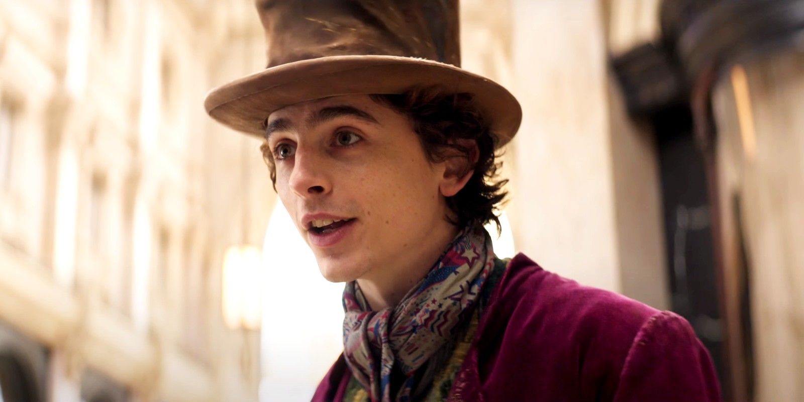 Timothee Chalamet dressed as Willy Wonka with the tall hat and purple coat in Wonka
