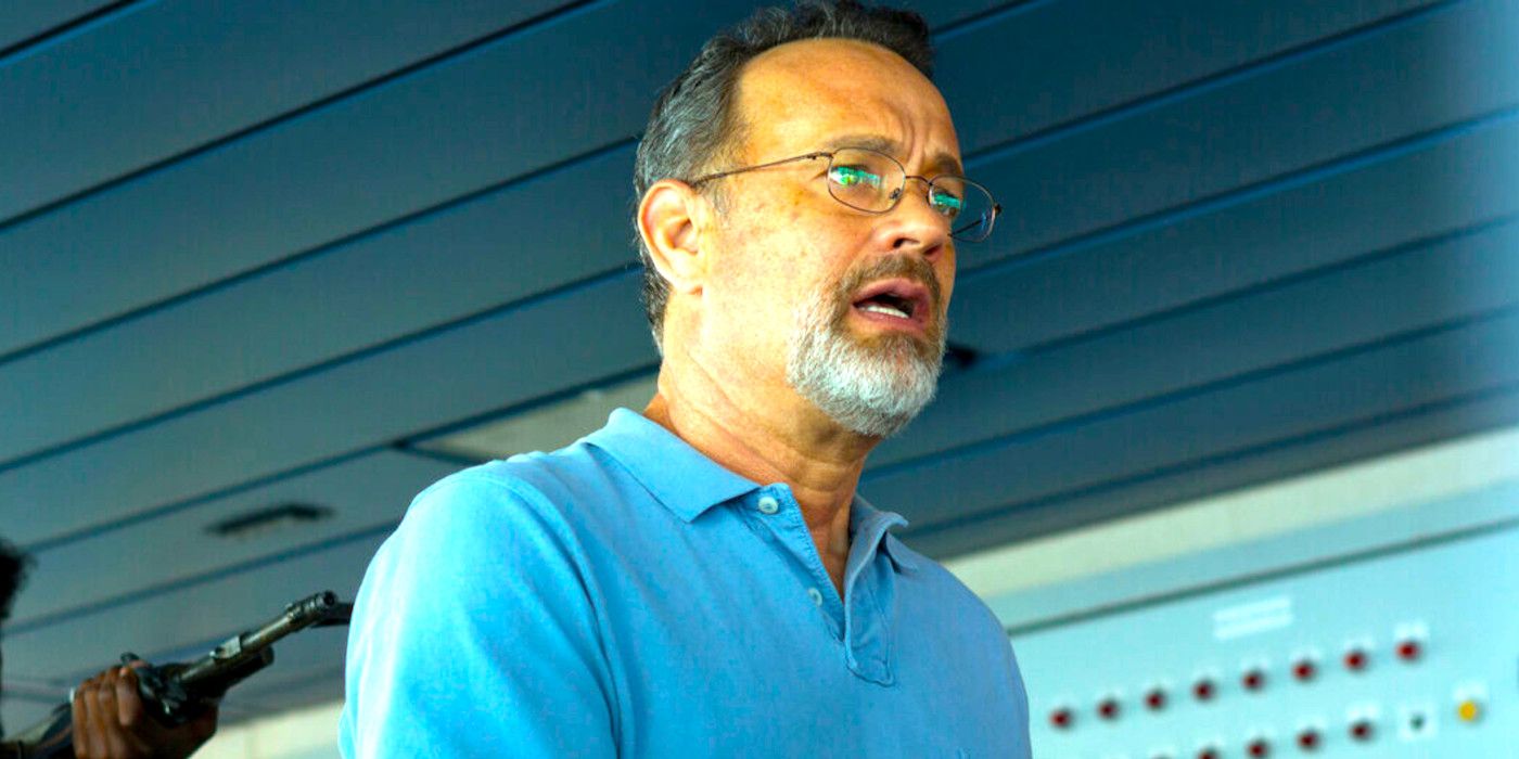 Tom Hanks in Captain Phillips looking alarmed as a man holds a machine gun to his back