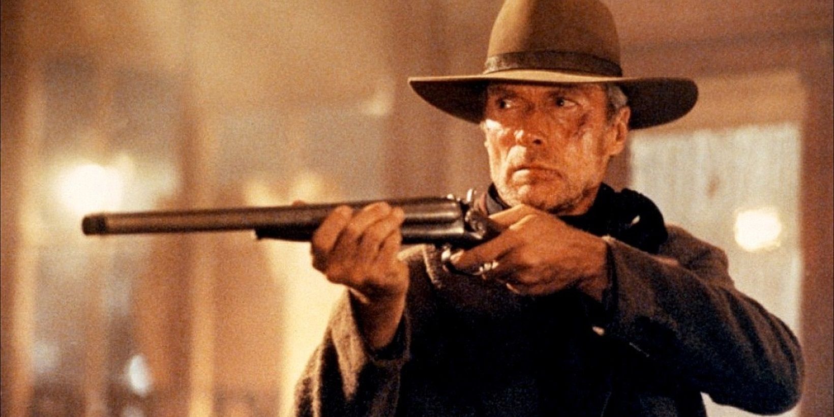 Clint Eastwood as Will Munny holding up a rifle in Unforgiven