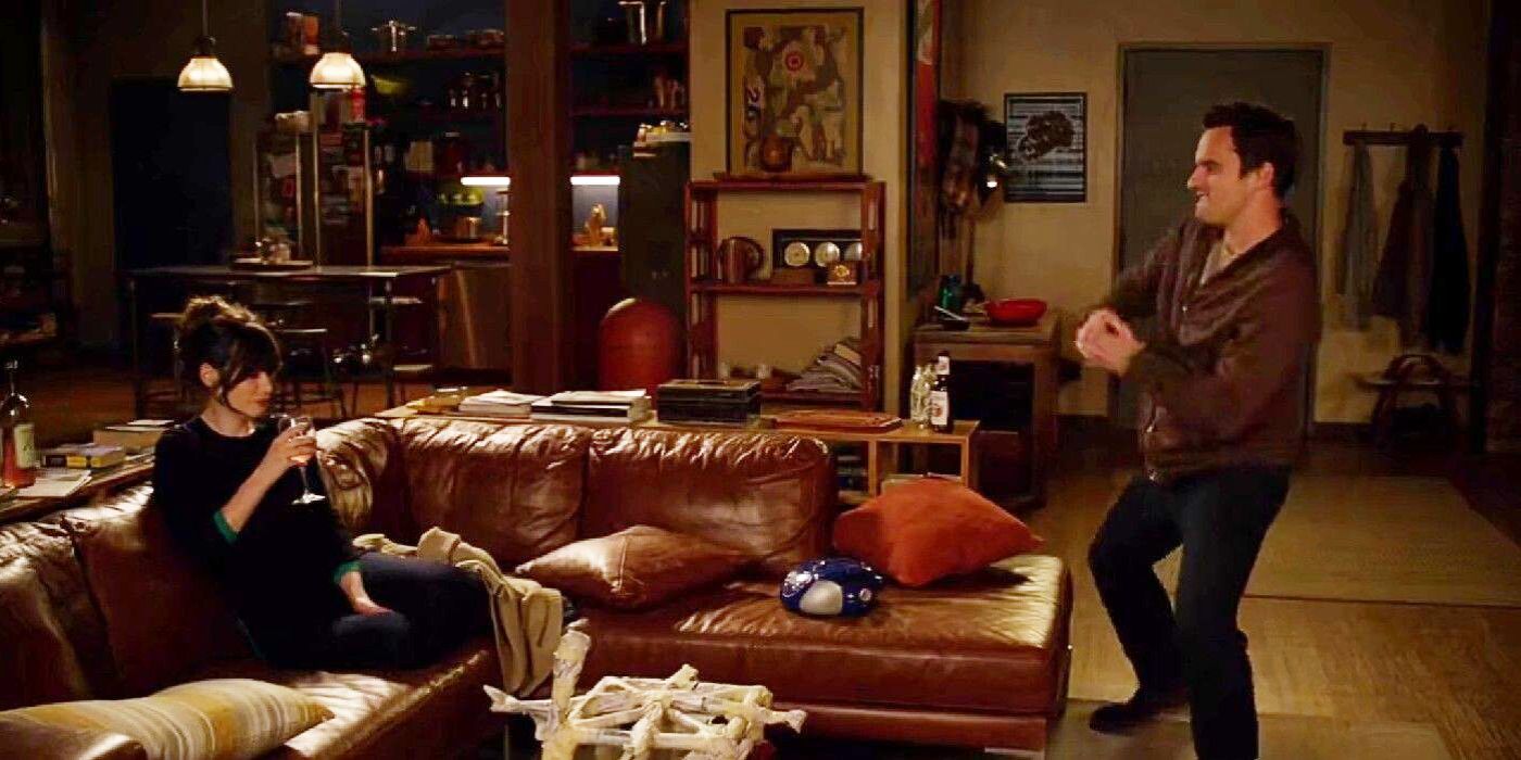 A scene from New Girl where Jess sits on the couch with a glass of wine as Nick does a silly dance in front of her