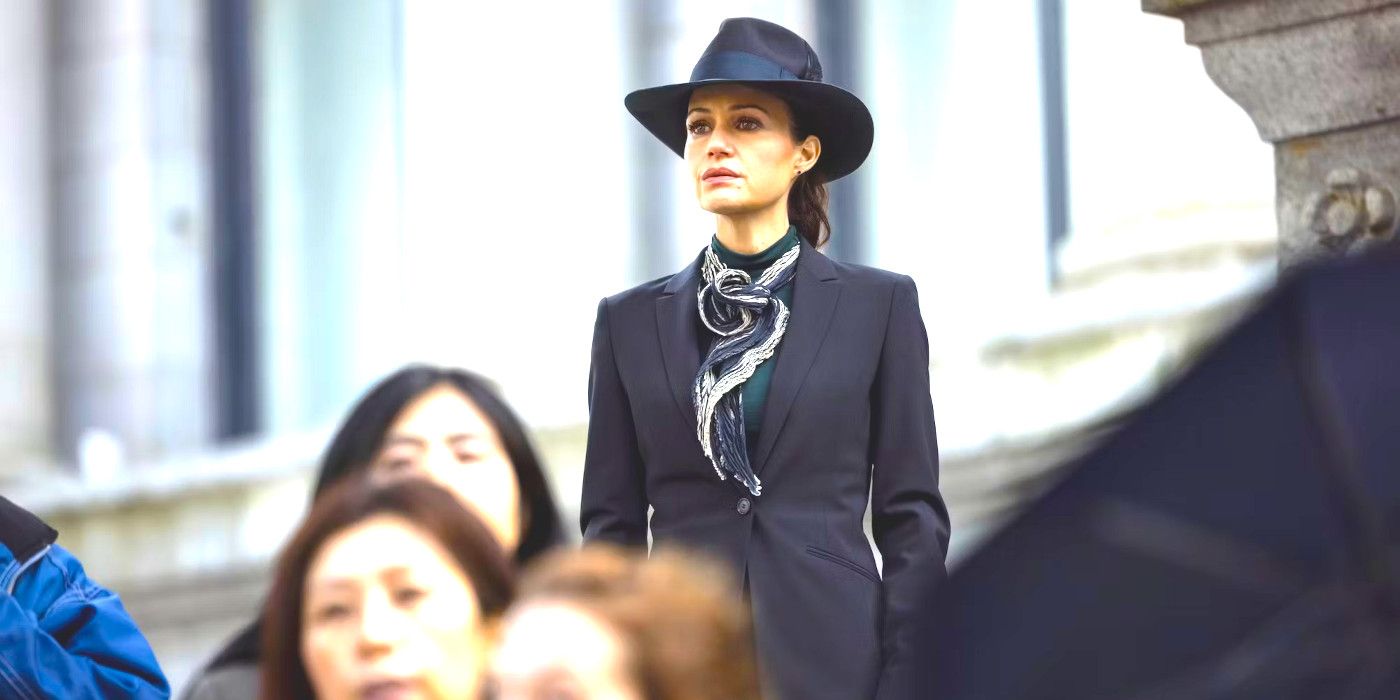 Carla Gugino wearing a sharp looking suit and standing in a crowd of people in The Fall of the House of Usher