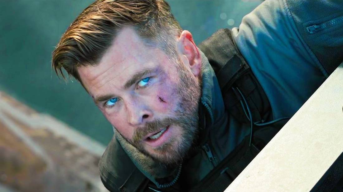 Tyler Rake pendurado em uma borda em Extraction 2