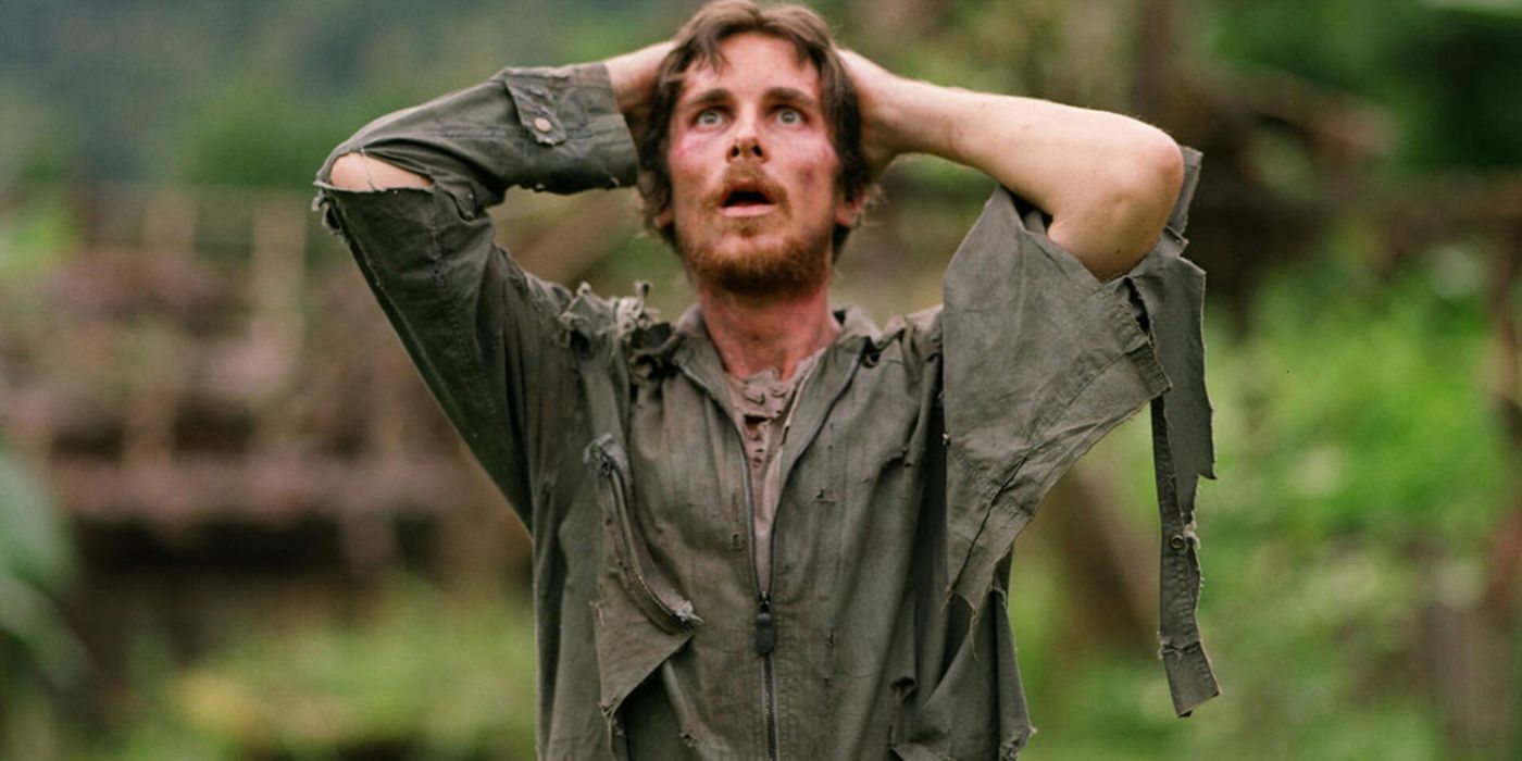 Christian Bale standing with his hands behind his head looking upwards in shock in Rescue Dawn