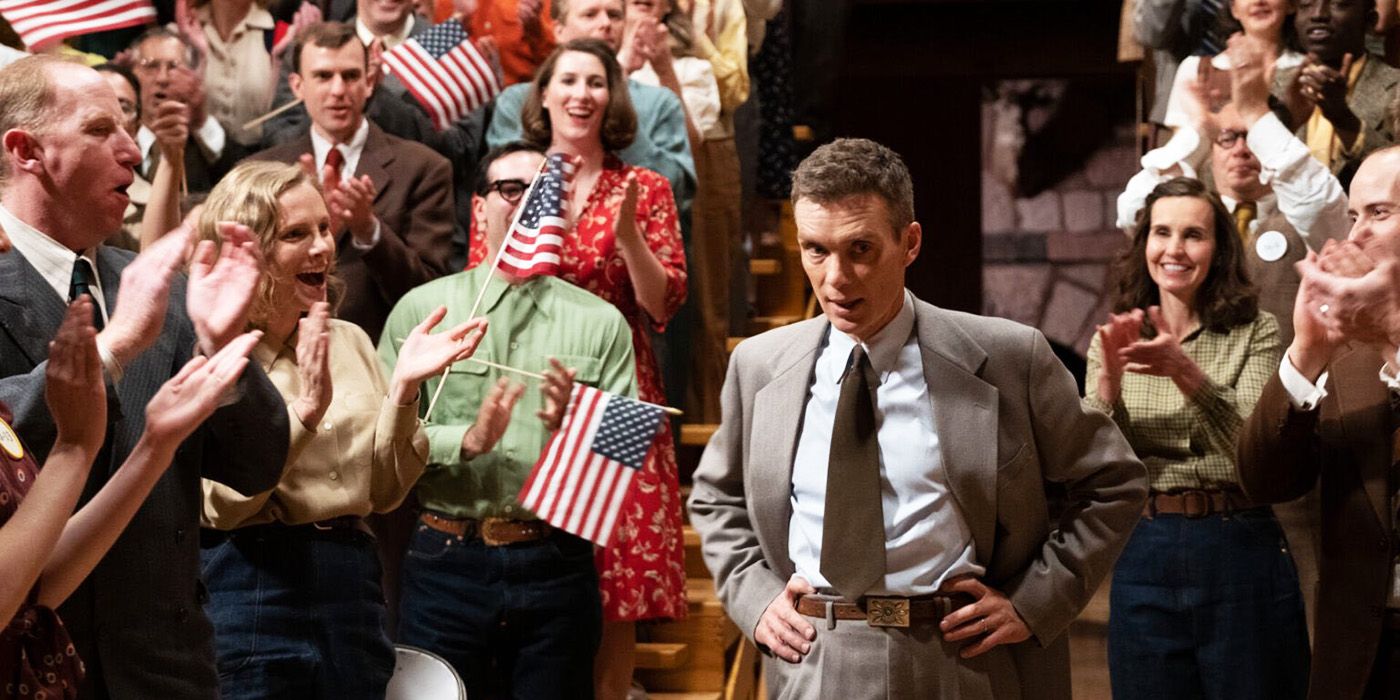 Cillian Murphy surrounded by a crowd holding American flags in Oppenheimer