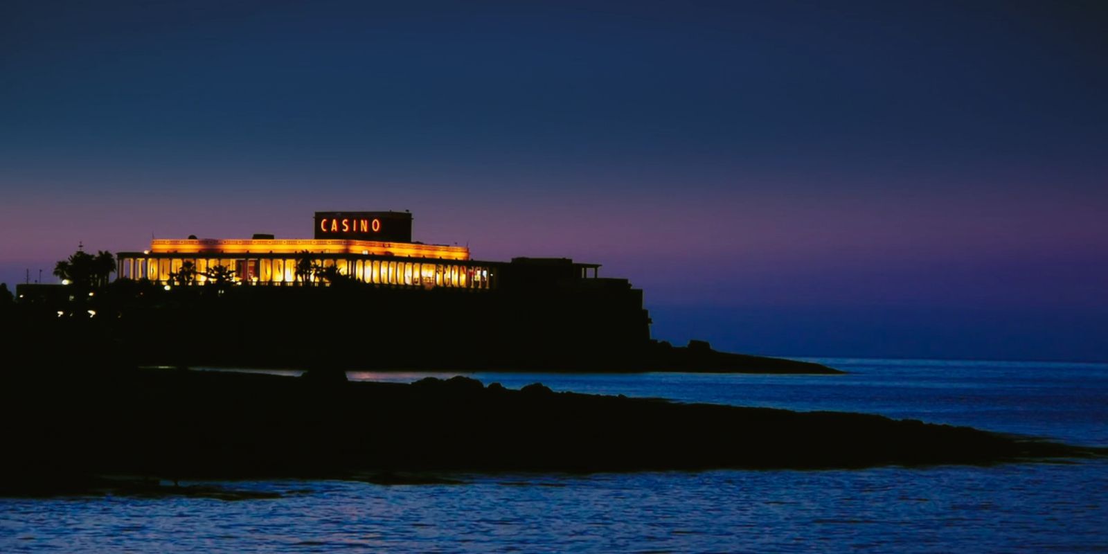 This image shows a lit up, elaborate casino at night.