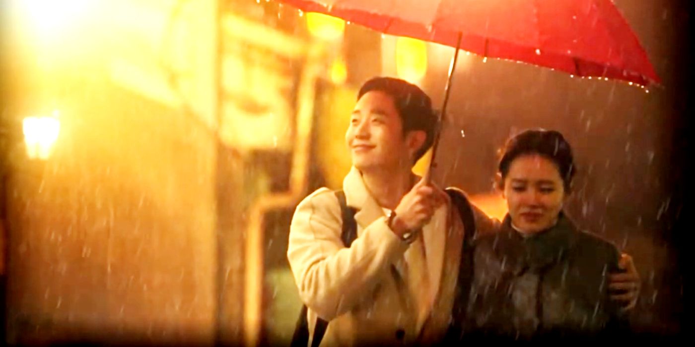 Hyun-woo and Soo-jin stand under an umbrella in the pouring rain.