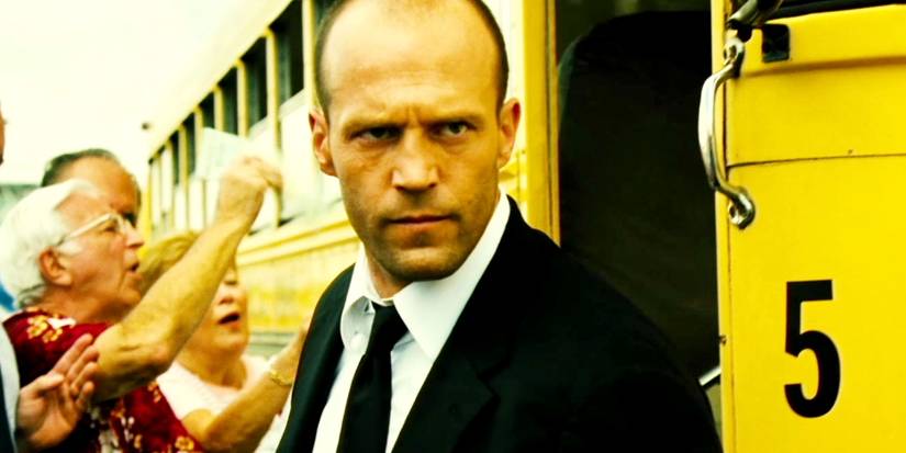 Jason Statham as Frank Martin standing in front of a school bus in Transporter 2.