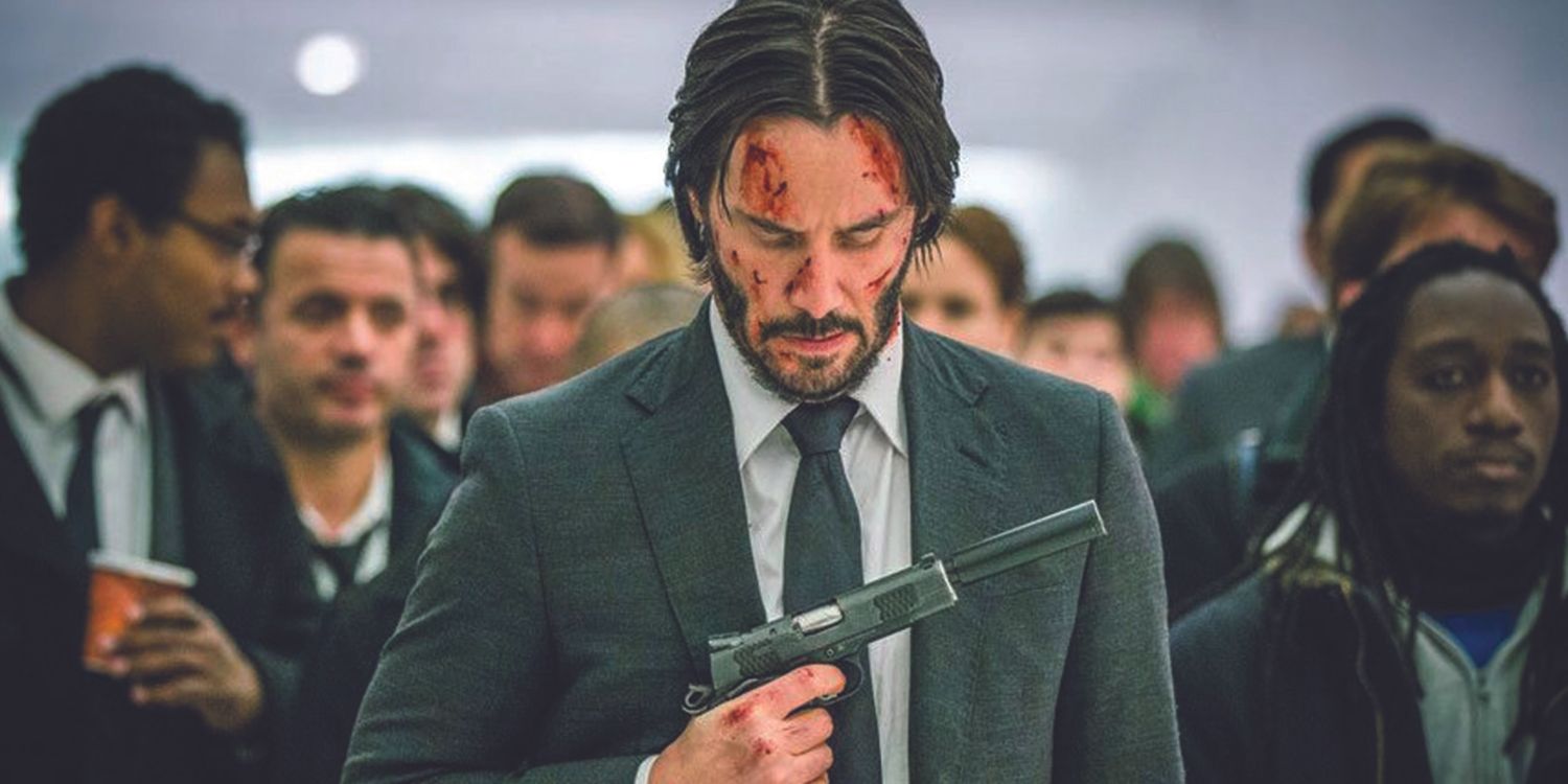 John Wick uses a silenced pistol amid a crowd in John Wick Parabellum.