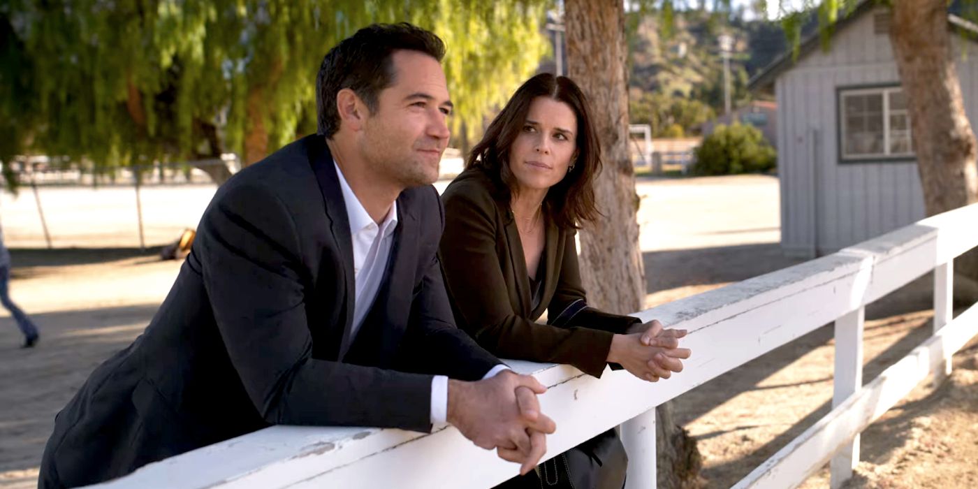Manuel Garcia-Rulfo and Neve Campbell Leaning Against a Fence in The Lincoln Lawyer Season 2