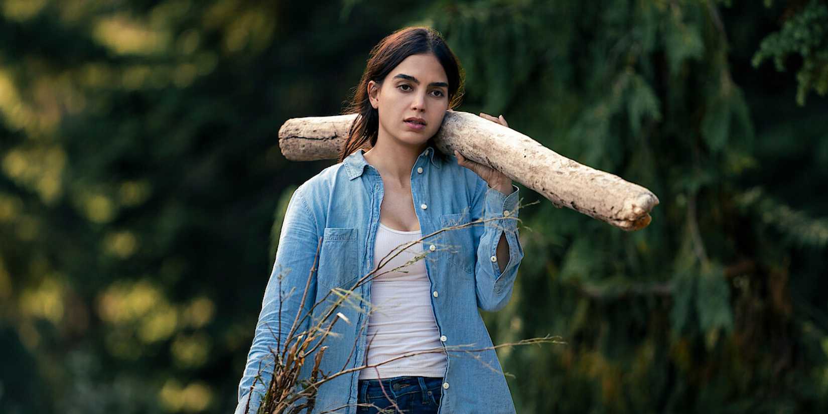 Melissa Barrera carying a branch as Liv in Keep Breathing