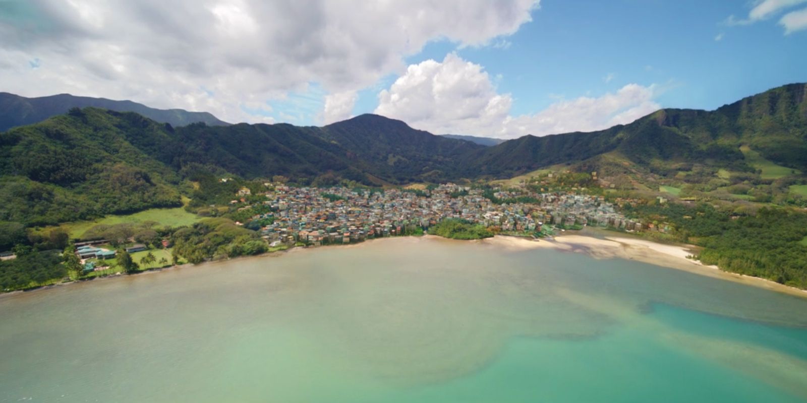 This image shows a town on the water with mountains behind it.