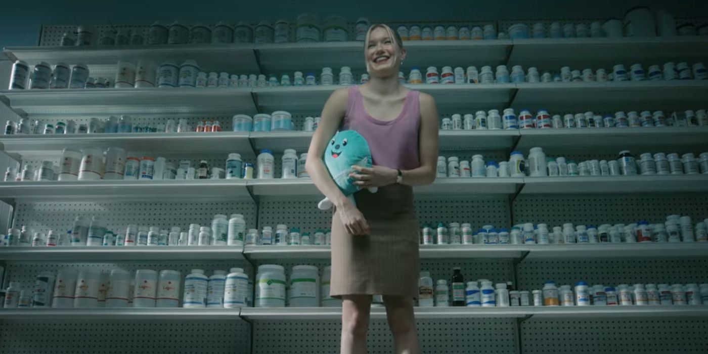 Shannon stands smiling in front of a wall full of medication bottles.