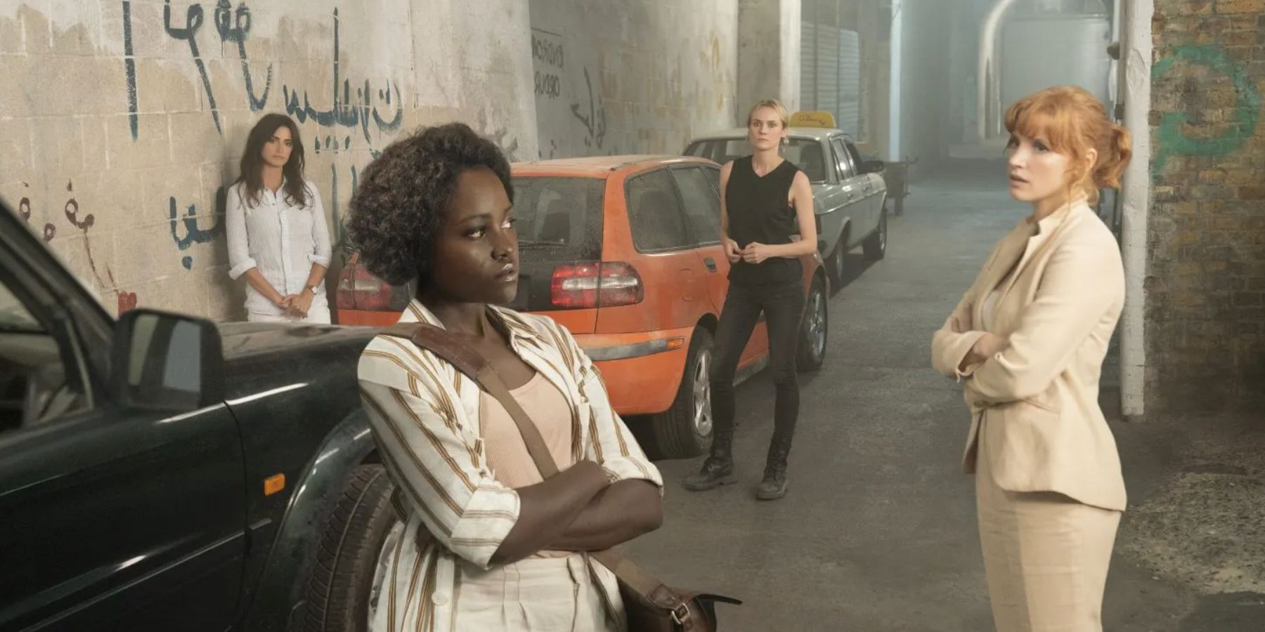 Penelope Cruz, Lupita Nyong'o, Diane Krueger, and Jessica Chastain standing near parked cars in The 355